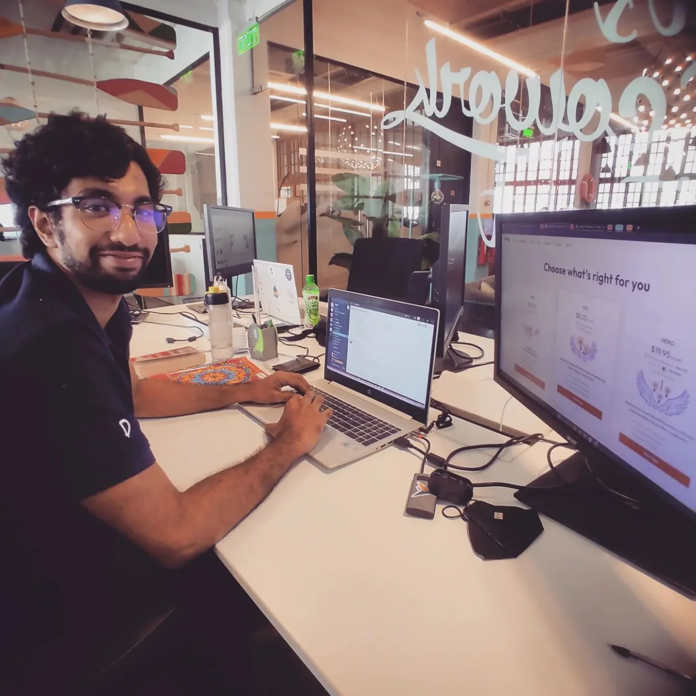 Tharaka at his desk in a Colombo office, turning to the camera with a smile.
